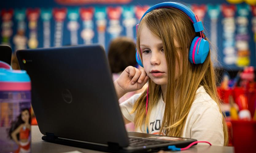 A girl with long hair uses a Chromebook